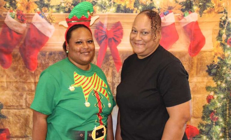 Two women standing in front of festive Christmas backdrop